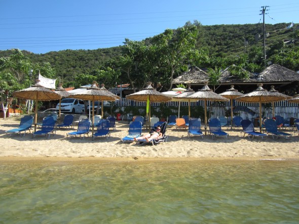 Julie slowly sliding off the deck chair into the sea with the Taverna 5 Steps in the Sand just behind.
